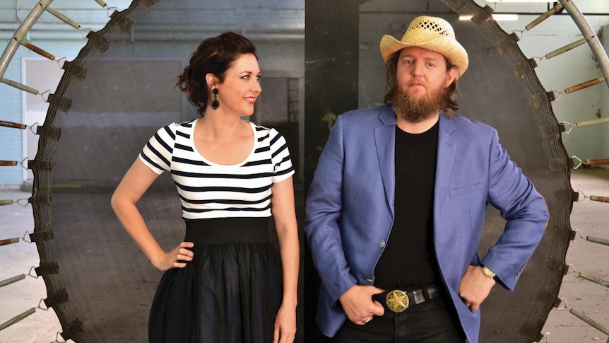 Taasha Coates and Tristan Goodall of The Audreys stand side-by-side in front of an upended trampoline.