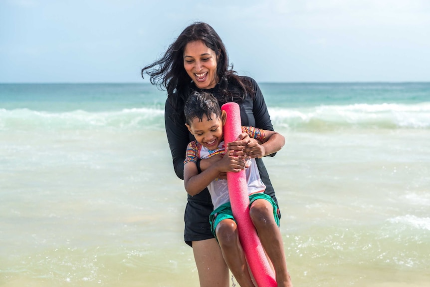 A woman plays with her son in the ocean.