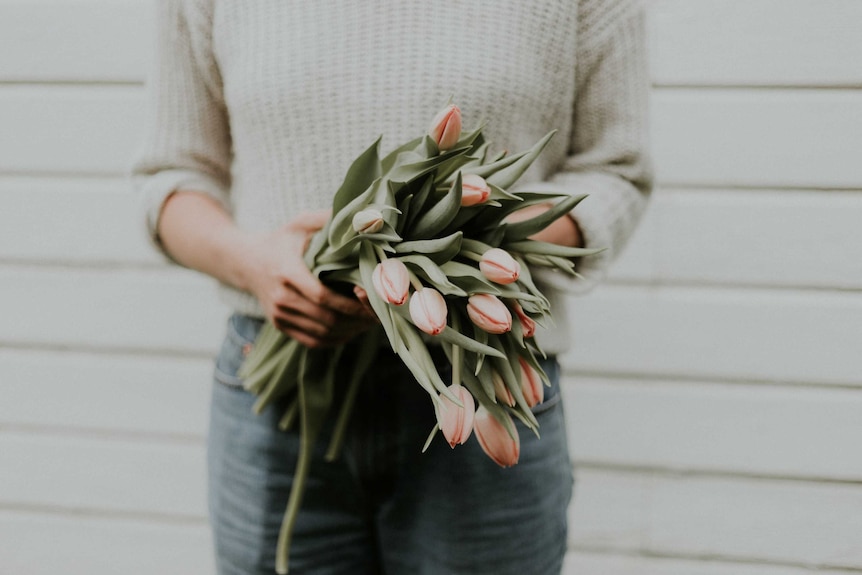 Person holding bouquet of orange tulips