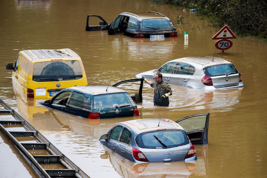 Rescuers search through cars submerged in floodwaters. 