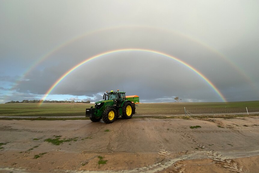 A rainbow stretches across a paddock
