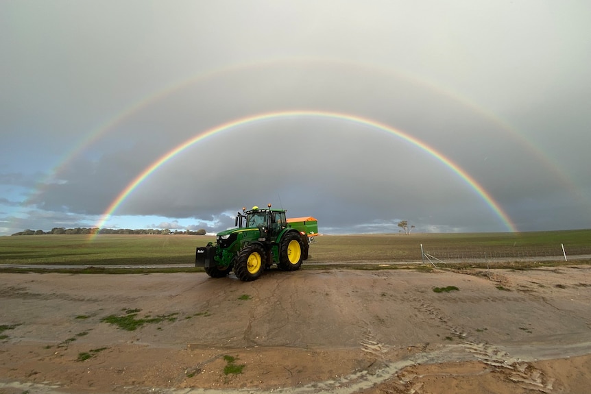 A rainbow stretches across a paddock