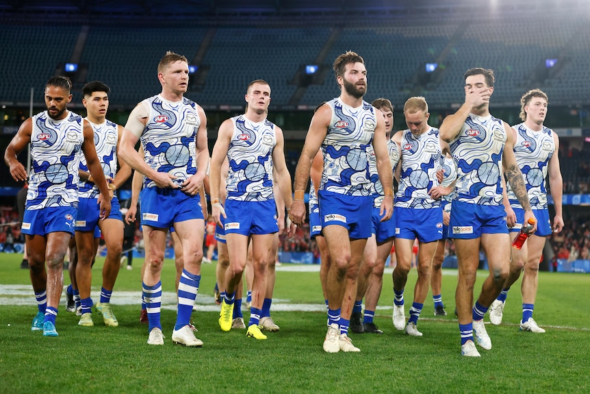North Melbourne players look disappointed as they walk off the field together