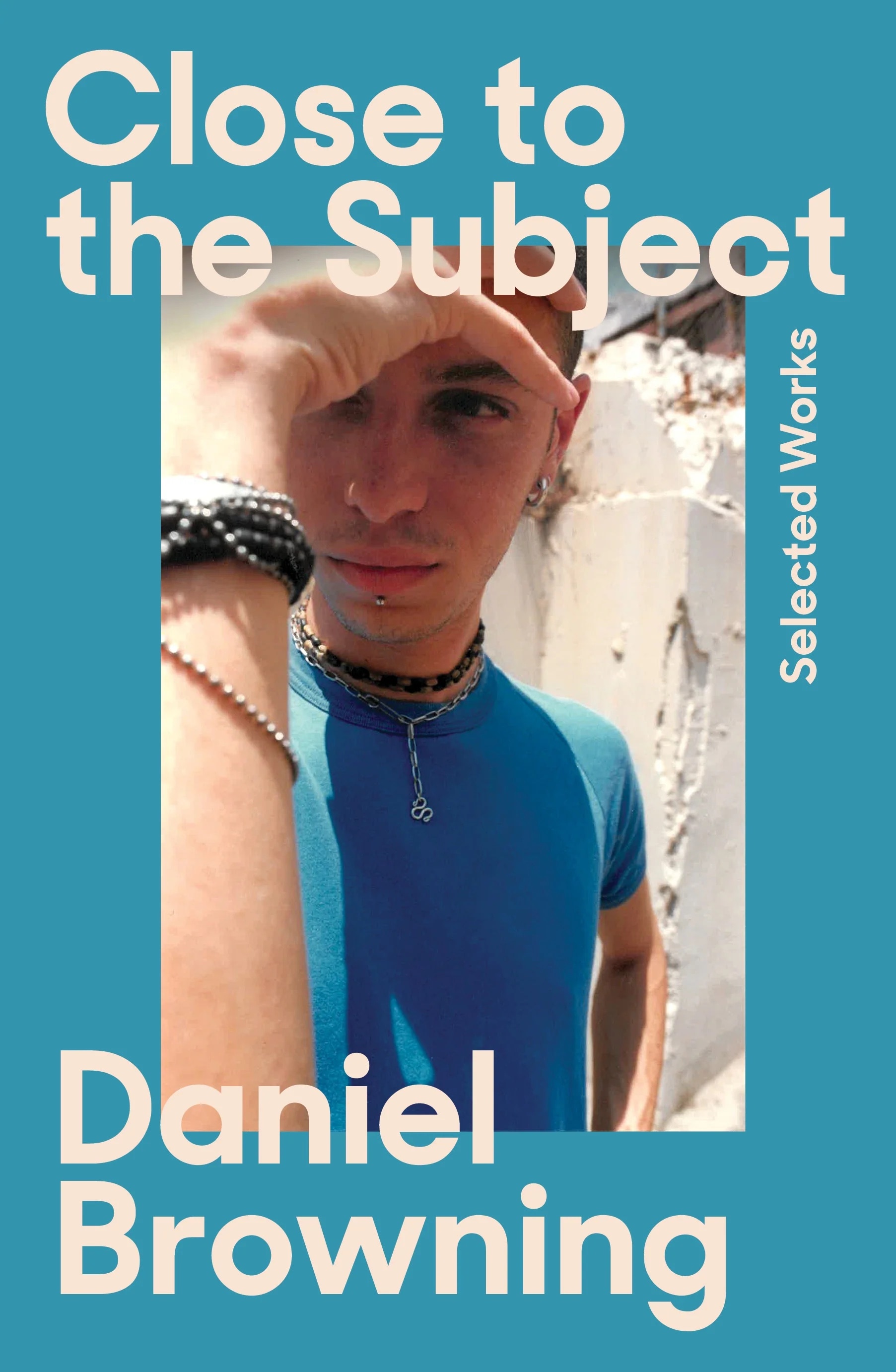 A book cover with a blue border showing a photograph of a young man wearing a blue t-shirt, with one hand shielding his eyes