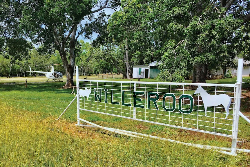 a gate with a helicopter and tree in the background