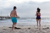 Nathan Morrissey and Jessie Vun run on the beach at Glenelg