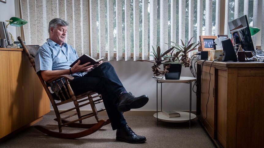 Grant Stewart reads a book while sitting on a rocking chair in his office at the East Doncaster Baptist Church in Melbourne.