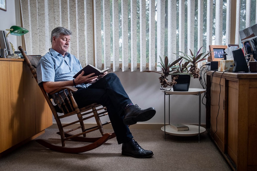 Grant Stewart reads a book while sitting on a rocking chair in his office at the East Doncaster Baptist Church in Melbourne.