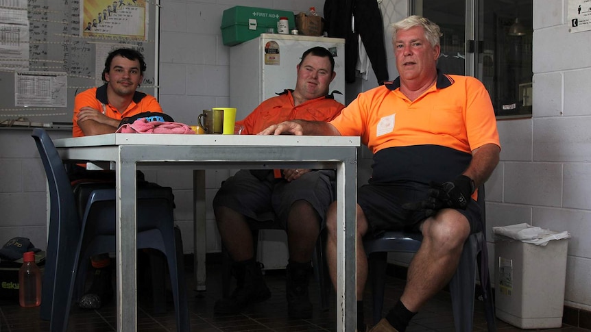 Darryl Farquharson sits at a table with two employees taking a lunch break.