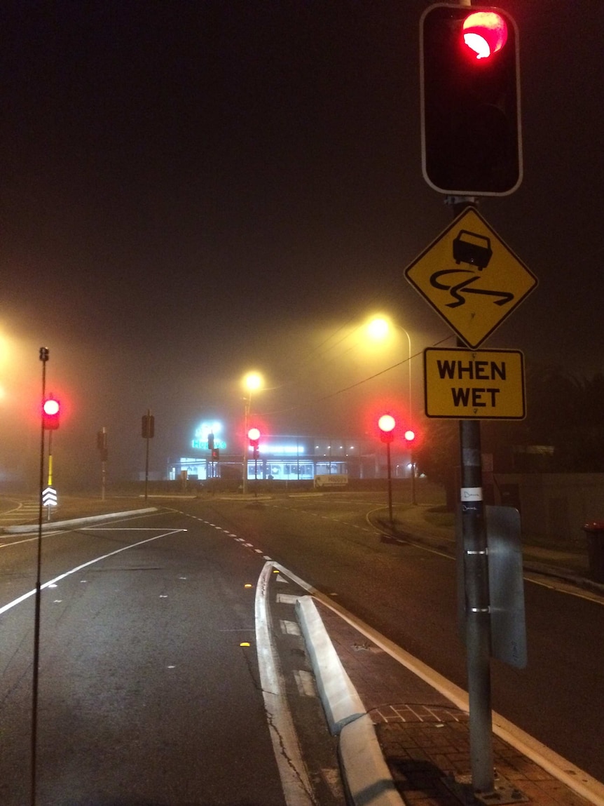 A car drives through early morning Brisbane fog