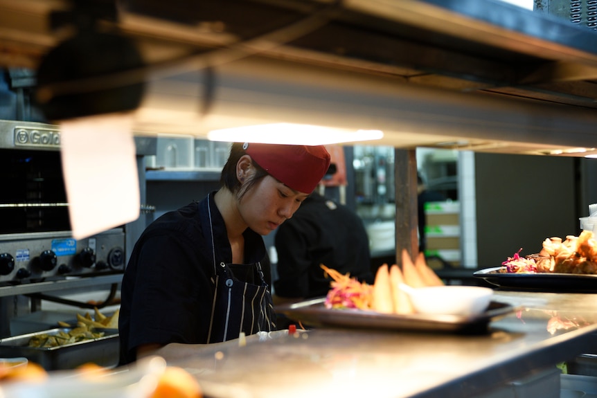 A chef behind the pass with food waiting to be served. 