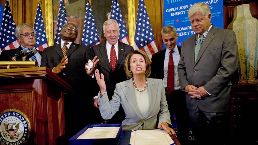 US Speaker of te House Nancy Pelosi (seated) prepares to sign the revised Wall Street bailout bill as House of Representatives members look on.