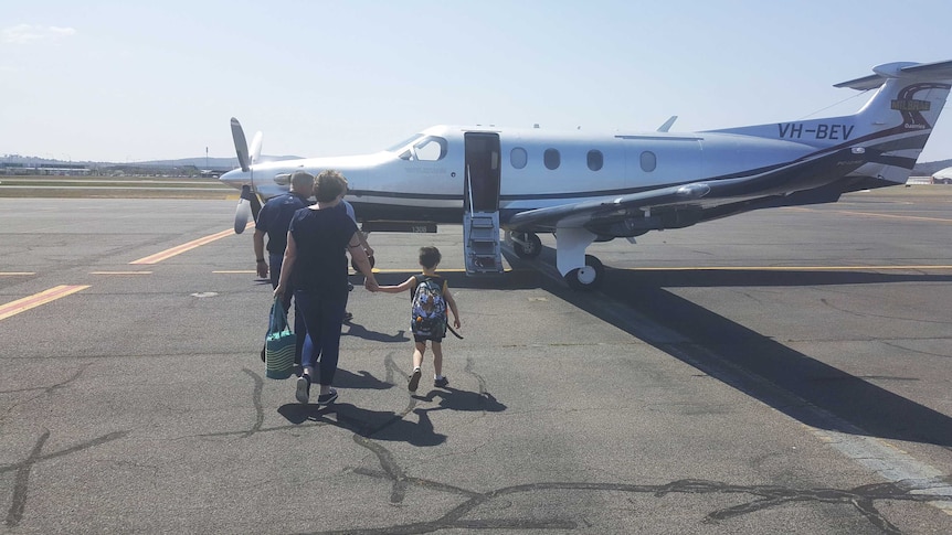 Neil Irwin with his mother and son walking up to the private aeroplane they took to his AFL grand final.