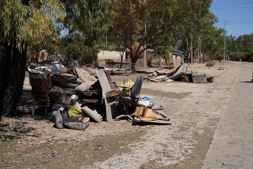 Damaged muddy household items outside houses on a brown road