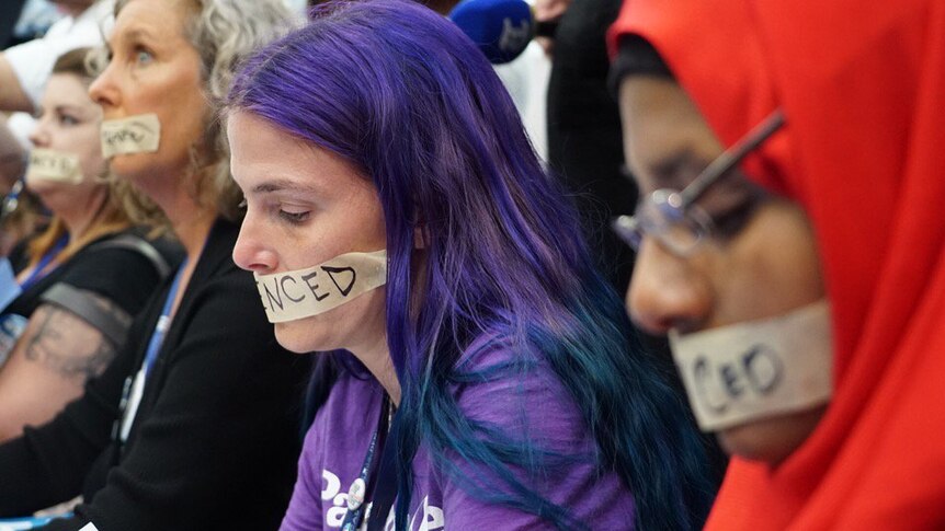 Bernie Sanders protestors in Democratic National Convention media tent wearing tape that reads "silenced" over their lips.