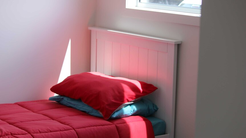 A bed by a window in a Supported Affordable Accommodation Unit.