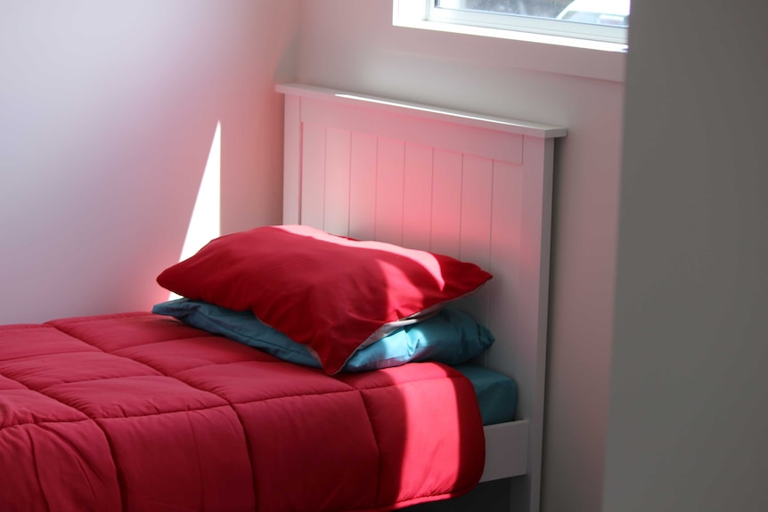 A bed by a window in a Supported Affordable Accommodation Unit.