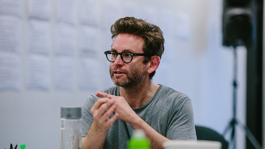 Colour close-up photo of Artistic Director of Queensland Theatre Sam Strong sitting at table in rehearsal room.