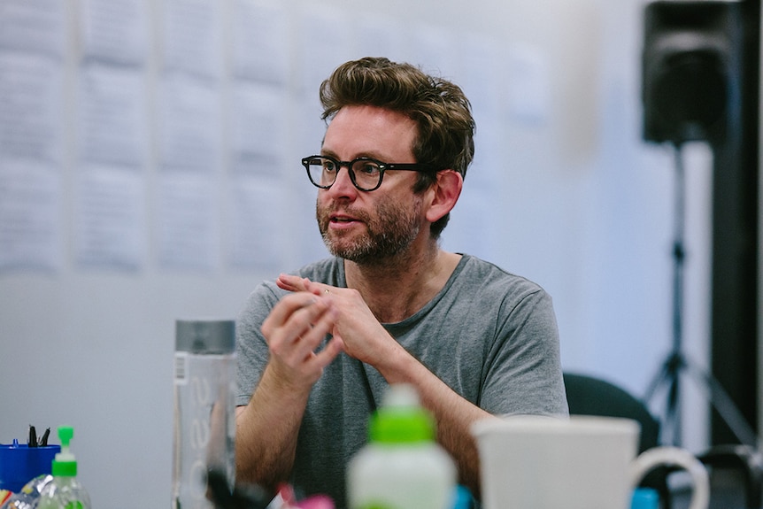 Colour close-up photo of Artistic Director of Queensland Theatre Sam Strong sitting at table in rehearsal room.