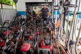 Man stands with a large line of mowers.