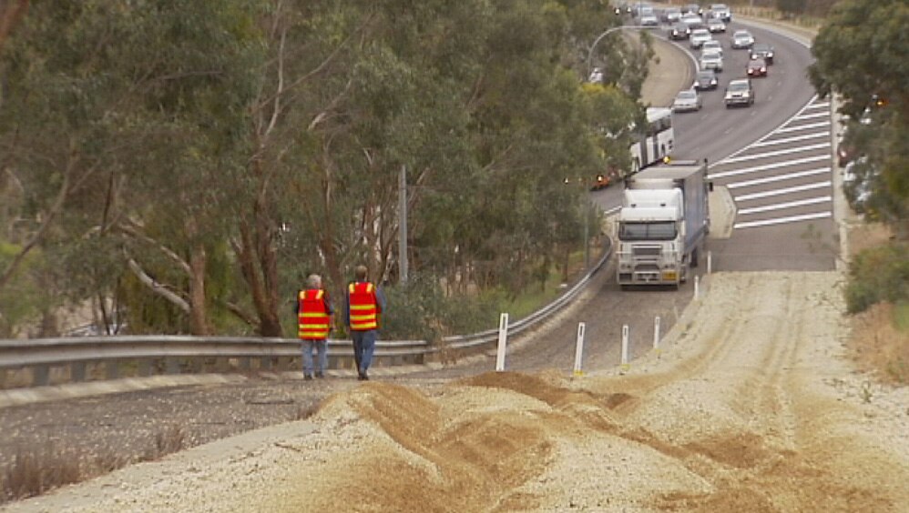 A truck on a gravel path near a freeway