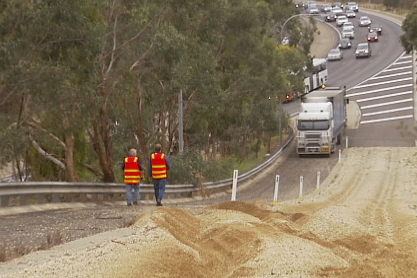 A truck on a gravel path near a freeway