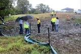 Groups of people stand in a muddy field.