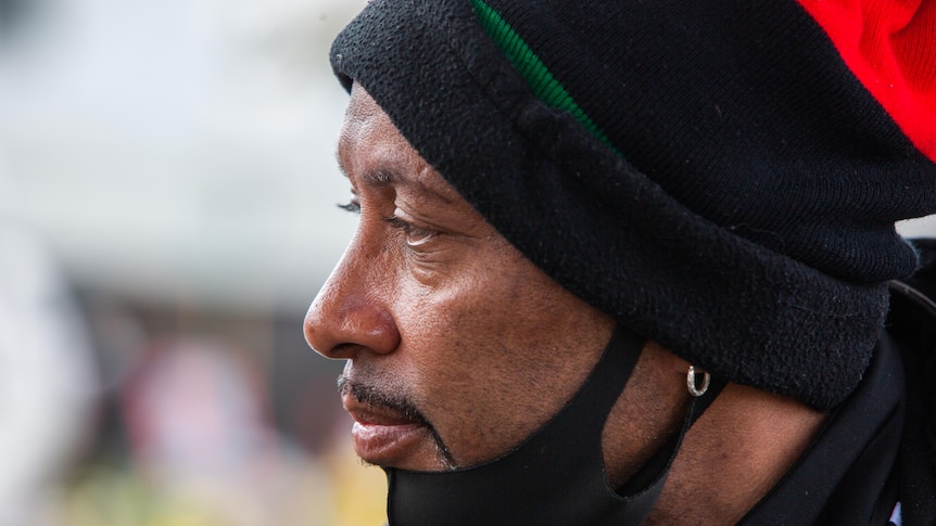 A man in a black hat looks into the distance