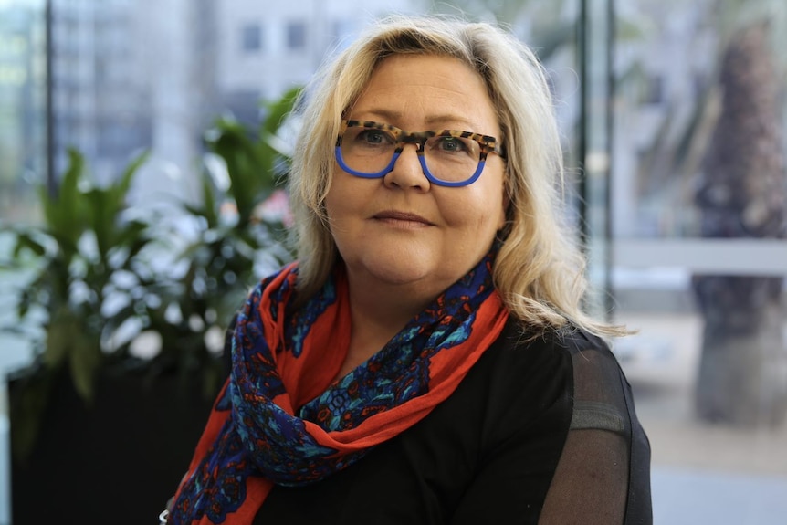 A portrait of a woman with blonde hair and glasses with leopard print at the top half and blue on the bottom half.