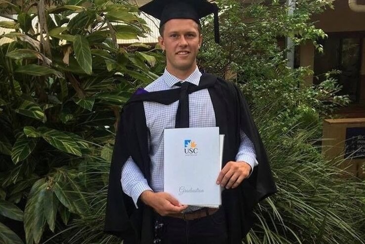 Young man in graduation outfit and certificate.