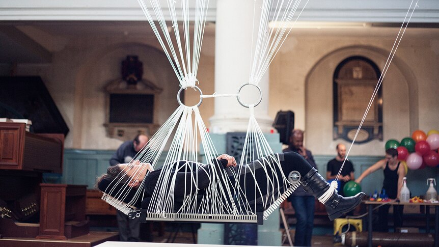 Colour photograph of artist Noëmi Lakmaier bound in ropes to a platform in her artwork Cherophobia.
