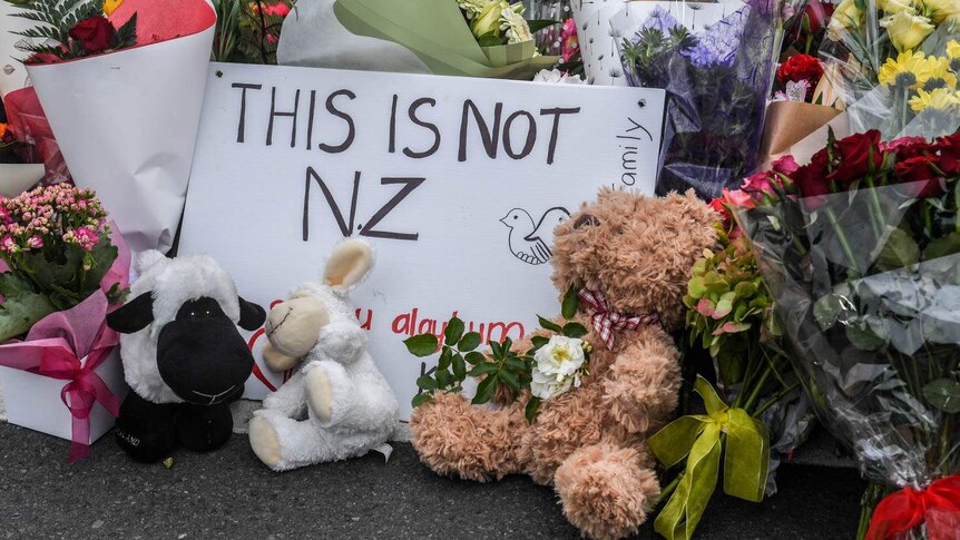 a sign reading this is not nz among flowers for Christchurch shooting victims outside the Christchurch Botanical Gardens