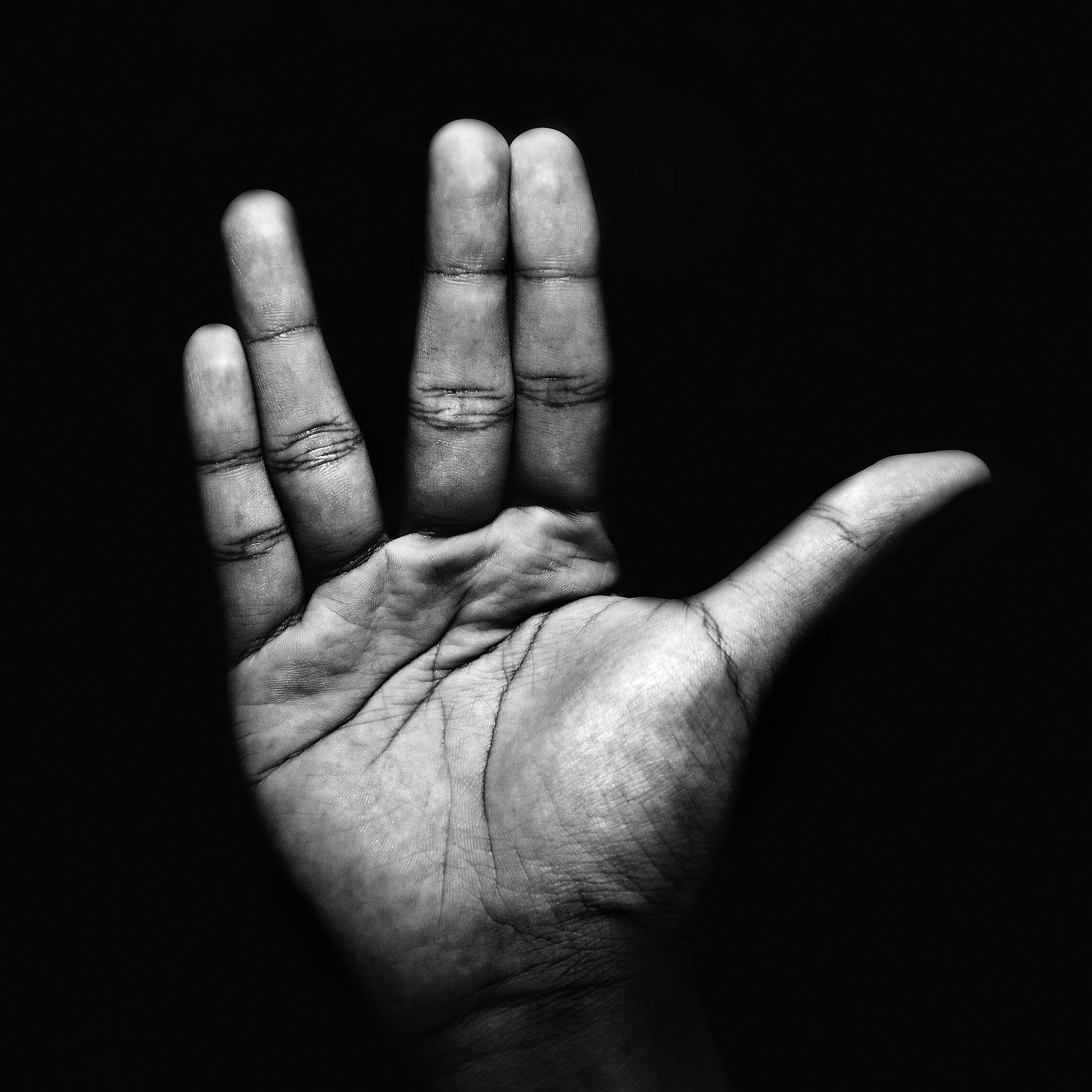 A palm with fingers paired in an unusual salute, two pairs of fingers together, and the thumb separate 