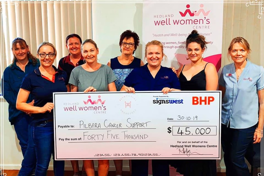 Eight women standing behind a large cheque for $45,000