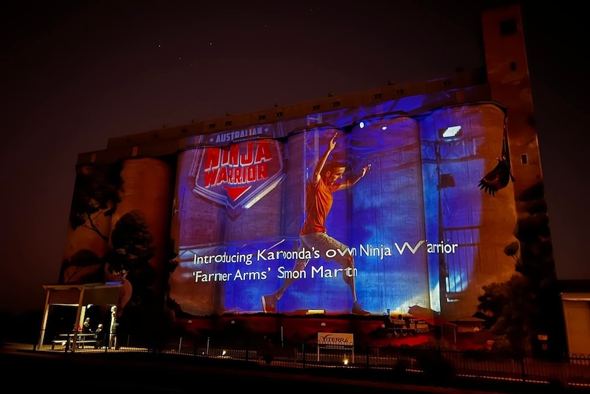 Silos at night with colourful images projected onto them.