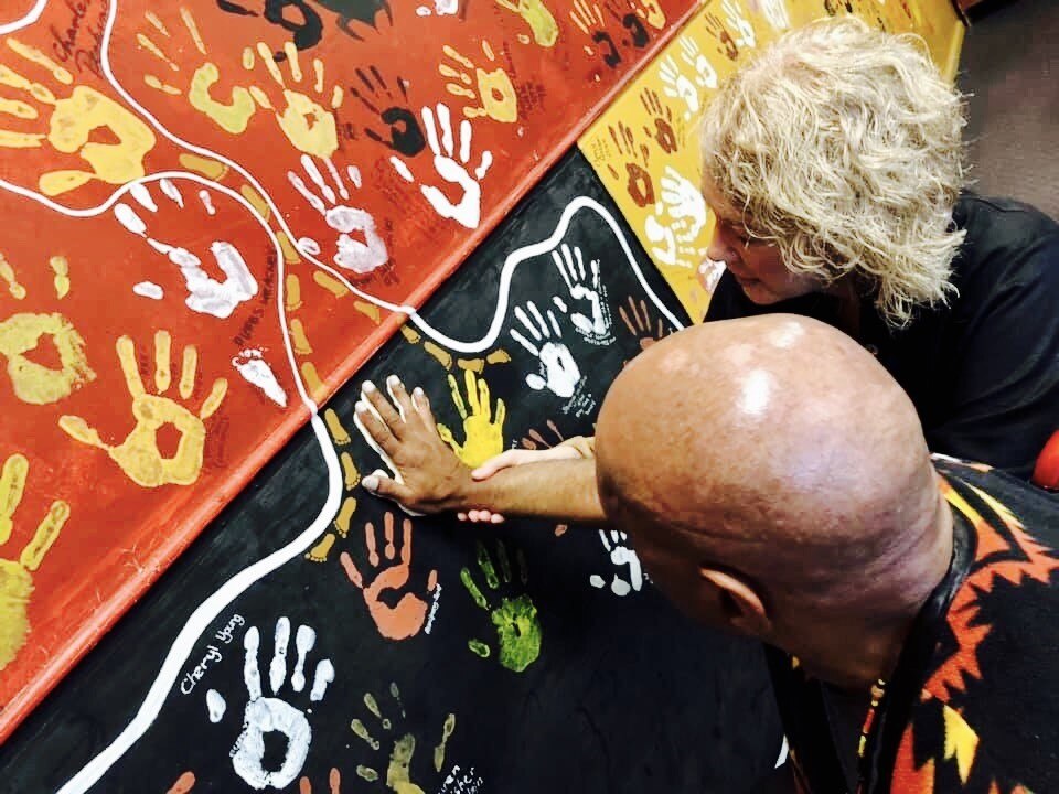 Archie Roach with Lisa Selsby as he put his handprint on a Gosford classroom wall.