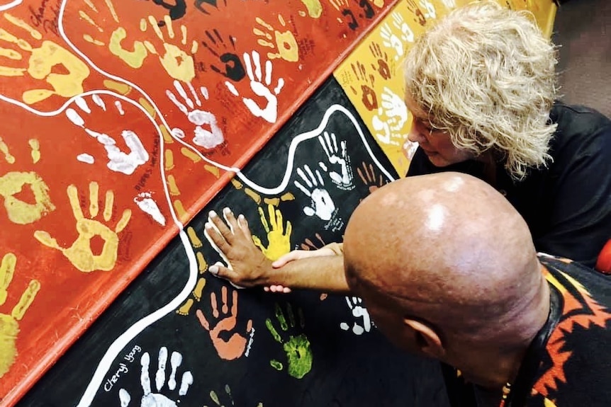 Archie Roach with Lisa Selsby as he put his handprint on a Gosford classroom wall.
