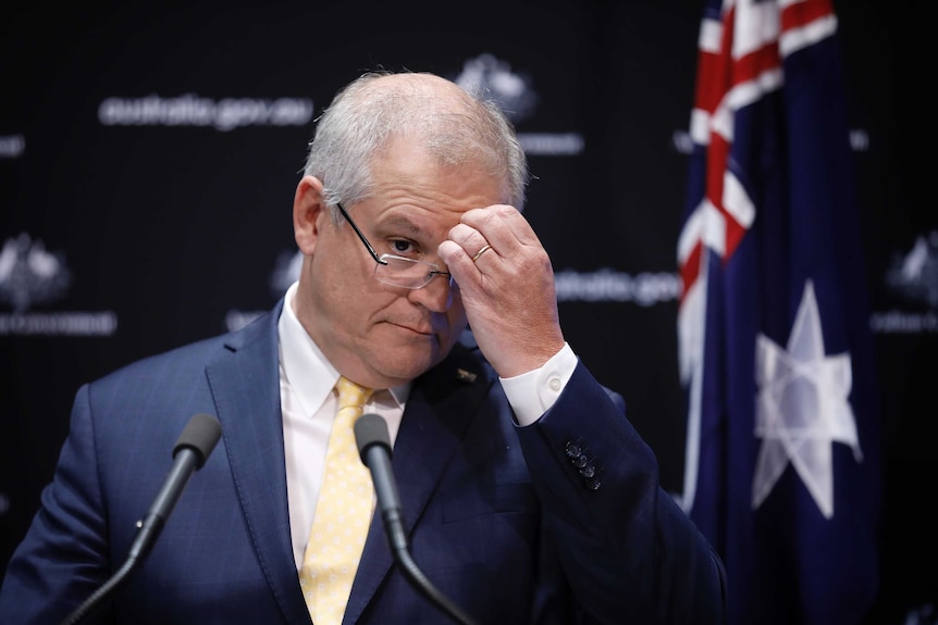 Tight front on shot of Morrison scratching his forehead.