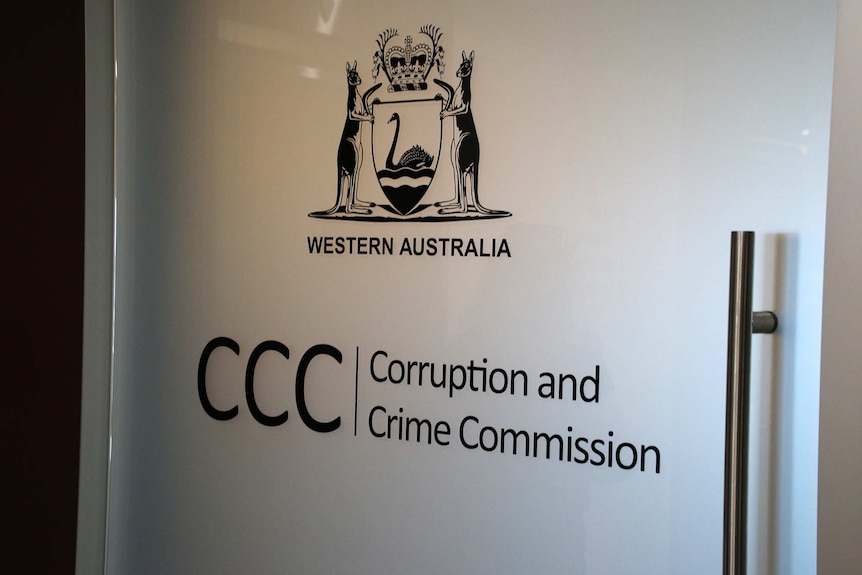 A sign and insignia on a white door at the WA Corruption and Crime Commission.