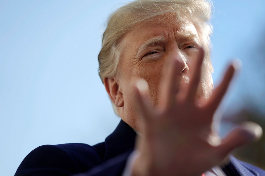 Donald Trump holds a hand out in front of the camera