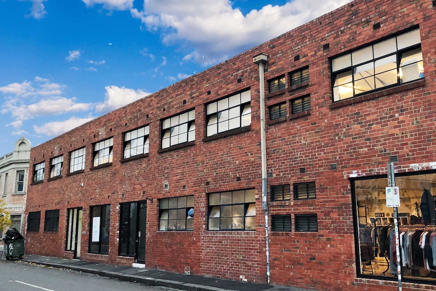 A red brick warehouse with multiple square glass windows.