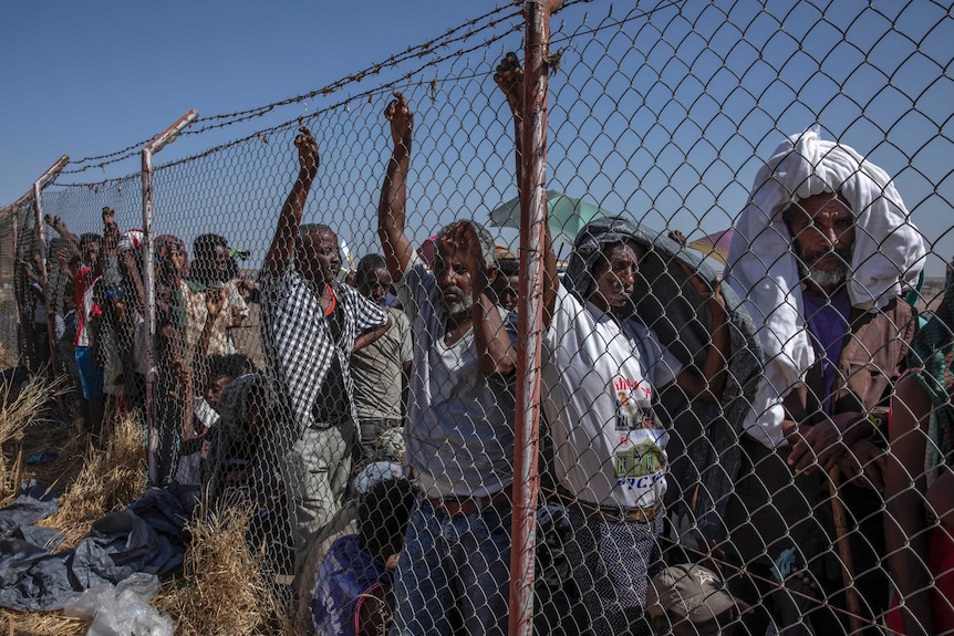 Tigray men who fled the conflict in Ethiopia wait for UNHCR to distribute blankets