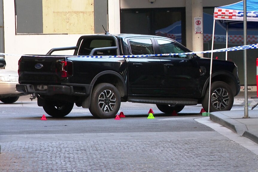A ute on a street surrounded by police tape.