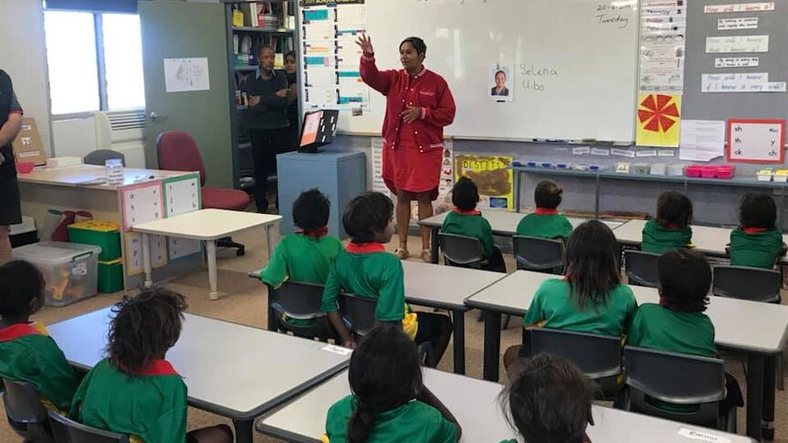 Selena Uibo stands before a classroom of students.