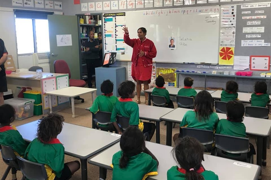 Selena Uibo stands before a classroom of students.