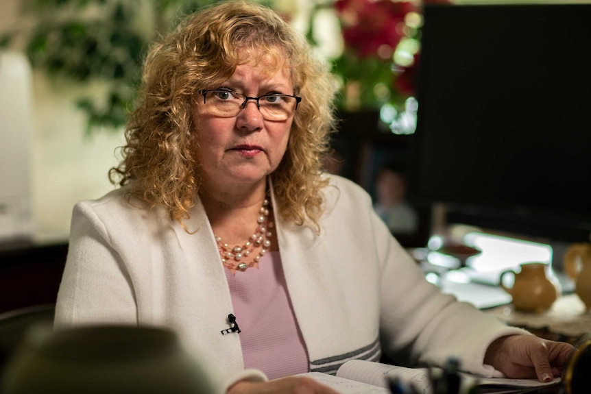 A woman in a white jacket sitting at a desk