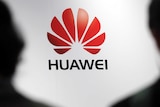 Huawei's logo with the silhouettes of two people in the foreground.