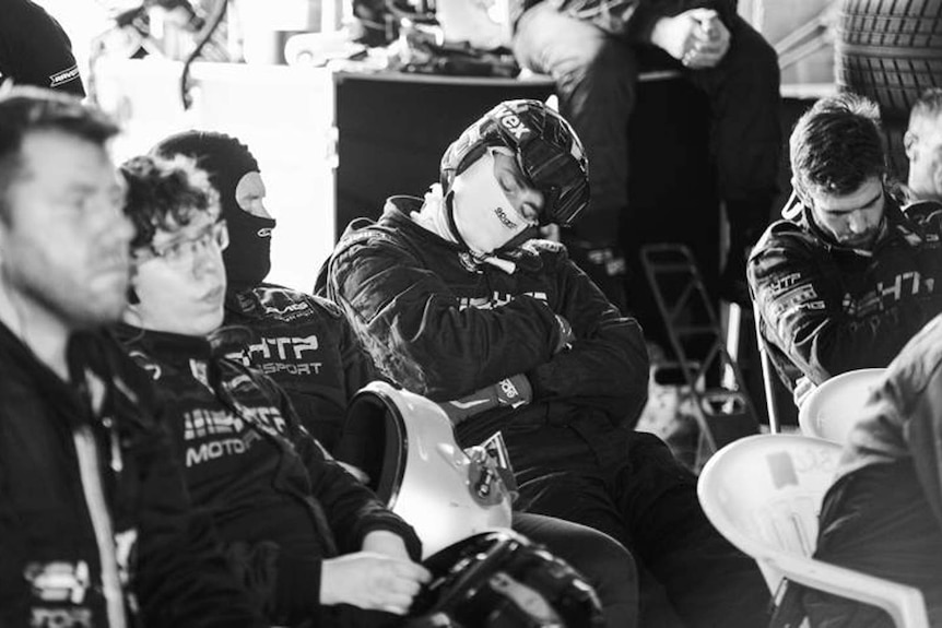 Black and white photograph of race car drivers resting