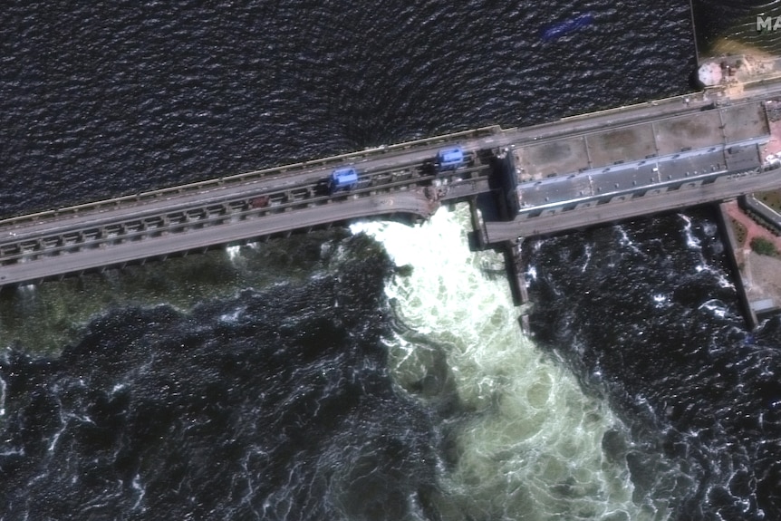 A satellite image of a dam wall rupture unleashing a flood of water.