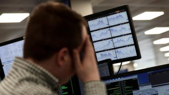 Un trader examine les informations financières sur les écrans d'ordinateur de l'indice IG sur le parquet de Londres